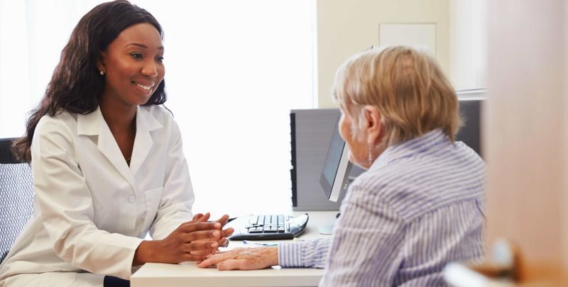 Pharmacist reviewing a medication list with a patient at a desk